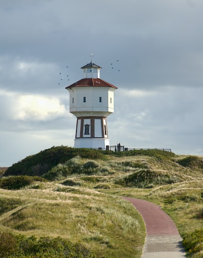 a white and brown lighthouse on top of a hill